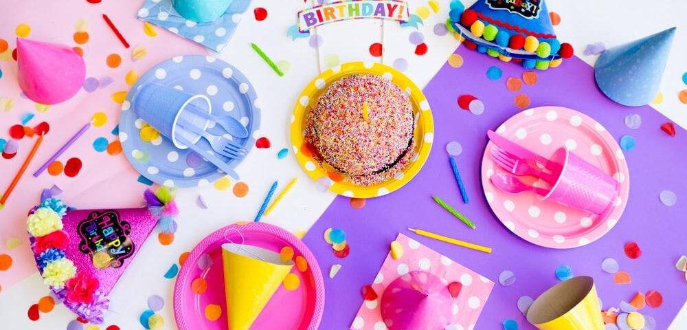 a birthday station with cake, plates, party hats, and confetti