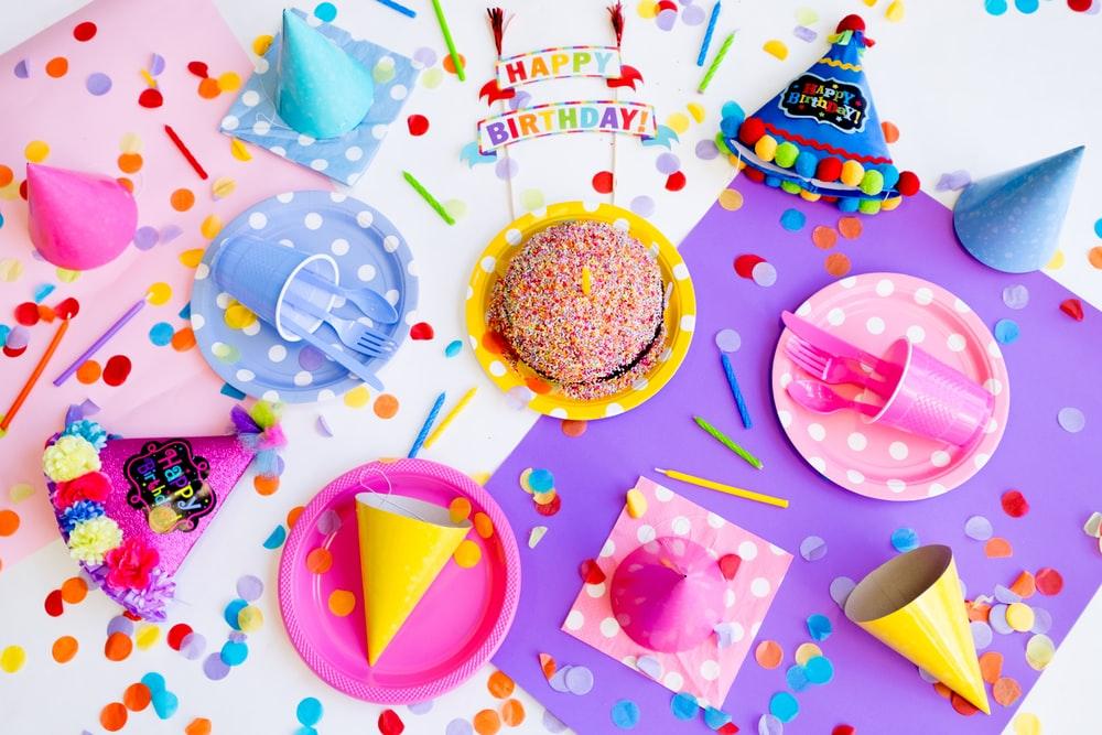a birthday station with cake, plates, party hats, and confetti
