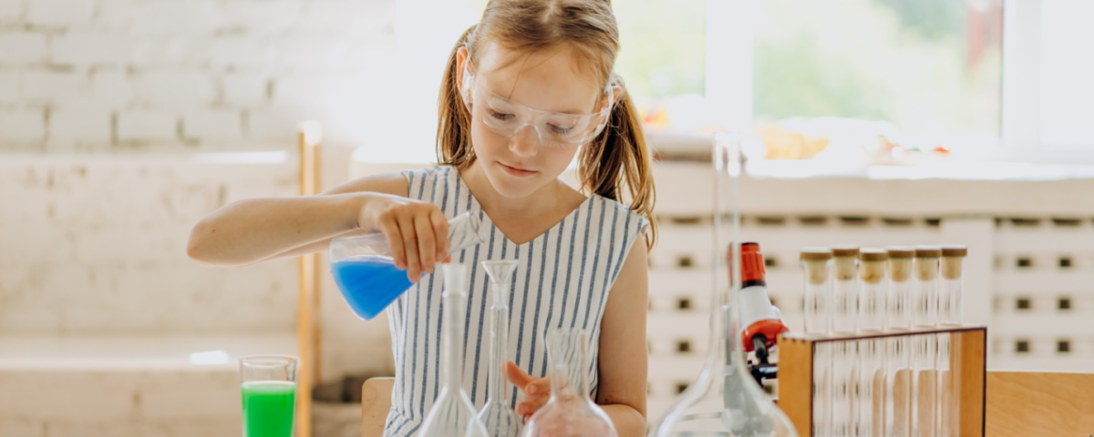 A girl holding a flask with a colored liquid inside it