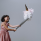 A girl in a pink dress hitting a piñata with a baseball bat