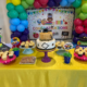 An image of a table decorated with balloons, cakes, and snacks