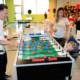 : a child playing foosball with adults