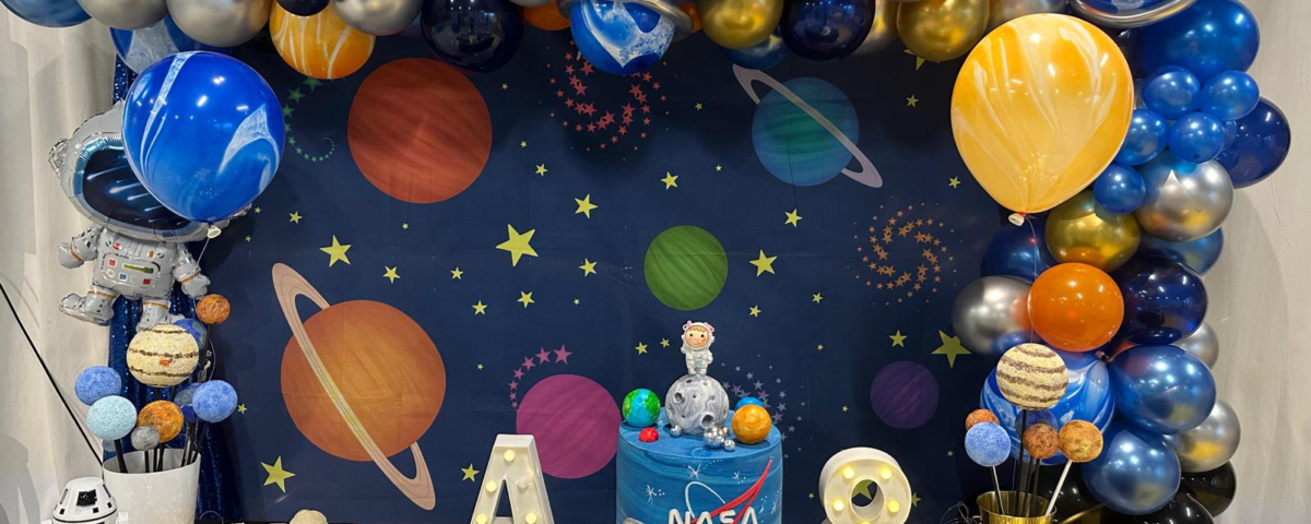 space-themed birthday party table with a balloon arch and space decorations