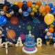 space-themed birthday party table with a balloon arch and space decorations