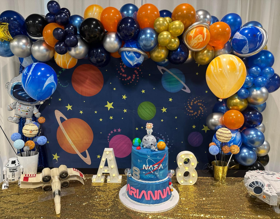 space-themed birthday party table with a balloon arch and space decorations