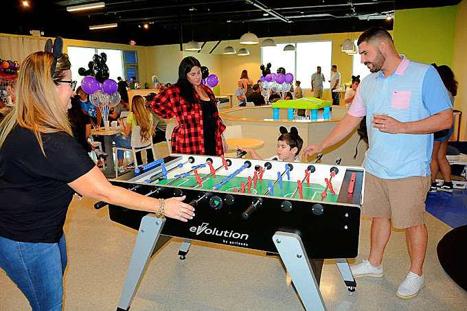 grown-ups playing on a foosball table at a kid’s party
